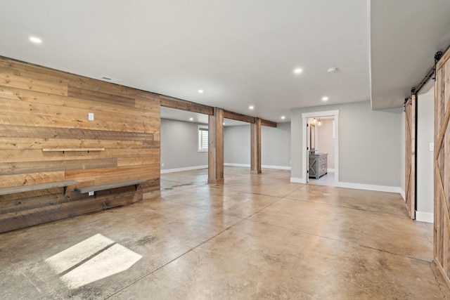 basement featuring a barn door and wood walls