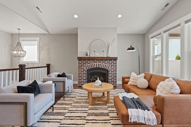 living room featuring an inviting chandelier, a fireplace, and light wood-type flooring