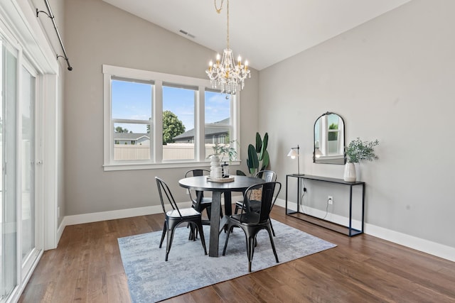 dining area featuring vaulted ceiling, hardwood / wood-style floors, and a notable chandelier