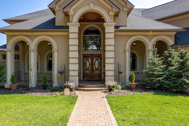 view of exterior entry with a lawn and french doors