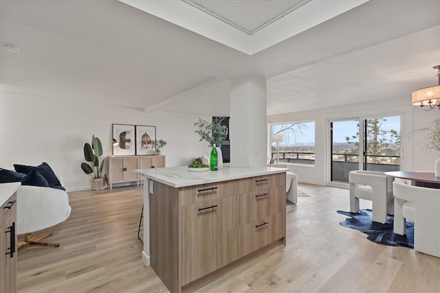 kitchen with a kitchen breakfast bar, a chandelier, light hardwood / wood-style floors, and a kitchen island