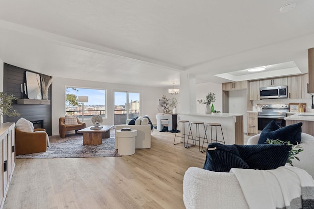 living room featuring a chandelier, a fireplace, and light wood-type flooring