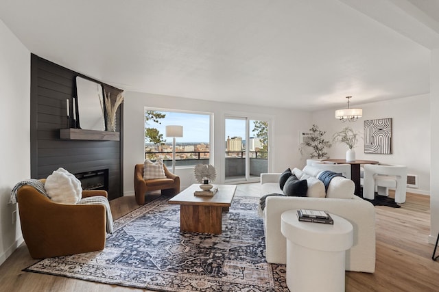 living room featuring hardwood / wood-style flooring, a fireplace, and an inviting chandelier