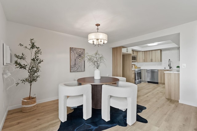 dining space with sink, a chandelier, and light hardwood / wood-style flooring