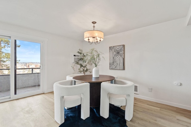 dining area featuring hardwood / wood-style flooring, a wall mounted AC, and a notable chandelier