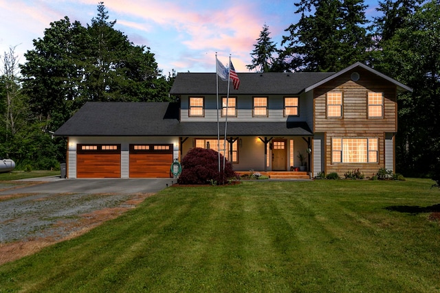 view of front of house with a garage, covered porch, and a lawn