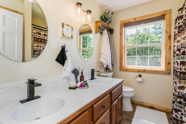 bathroom with vanity, toilet, hardwood / wood-style floors, and a wealth of natural light