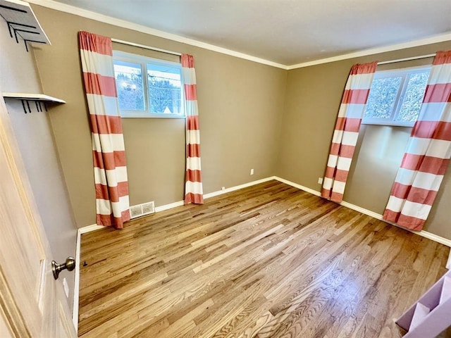 unfurnished room featuring hardwood / wood-style flooring, ornamental molding, and a healthy amount of sunlight