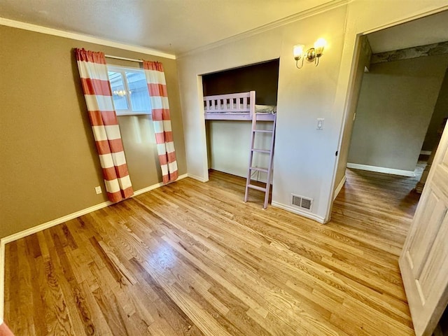 unfurnished bedroom featuring crown molding, light hardwood / wood-style floors, and a closet