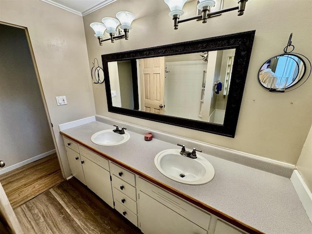 bathroom with crown molding, wood-type flooring, an inviting chandelier, and vanity