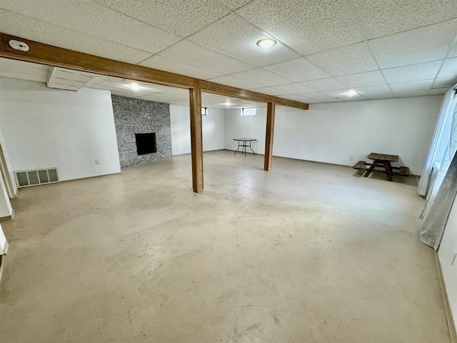 basement featuring a paneled ceiling and a brick fireplace