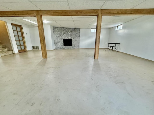 basement with a fireplace and a paneled ceiling