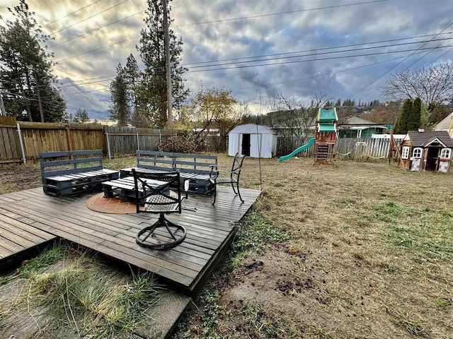 wooden terrace featuring a yard, a playground, and a shed