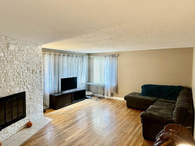 living room featuring a textured ceiling, a fireplace, and light hardwood / wood-style floors