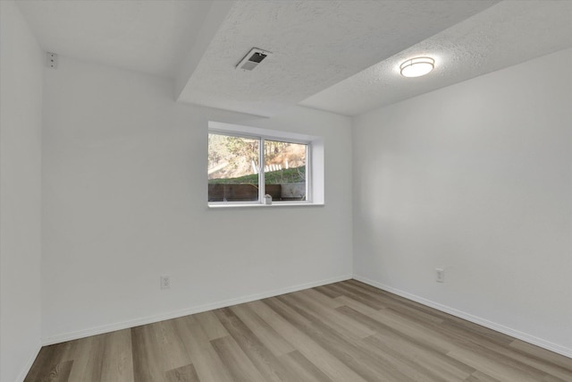 spare room featuring light hardwood / wood-style flooring and a textured ceiling