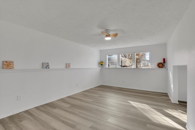 empty room with ceiling fan, light hardwood / wood-style flooring, and a textured ceiling