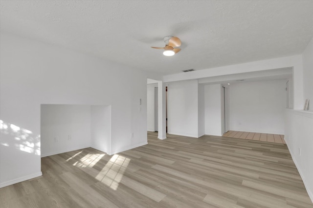 empty room featuring ceiling fan, light hardwood / wood-style flooring, and a textured ceiling