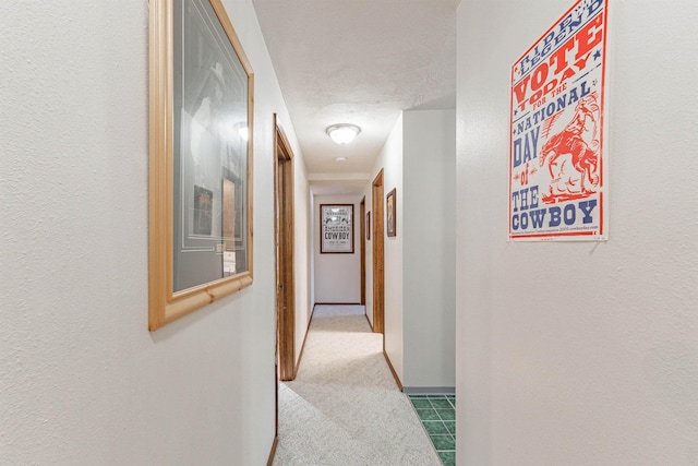 hall with light carpet and a textured ceiling