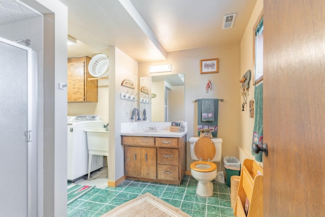 bathroom with vanity, toilet, washer / dryer, and a shower with shower door