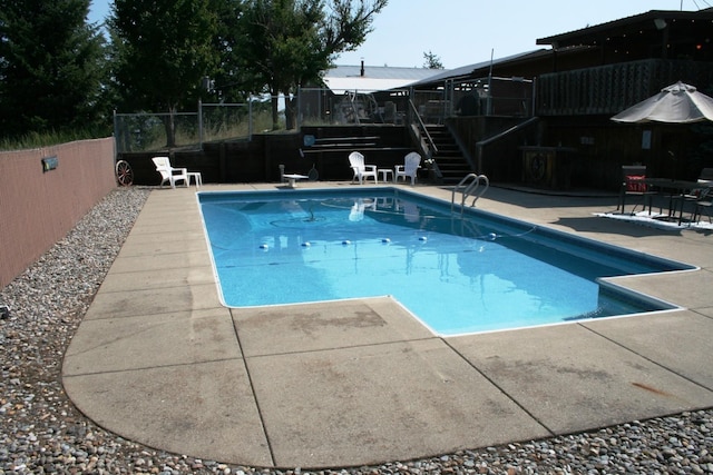 view of swimming pool with a diving board and a patio