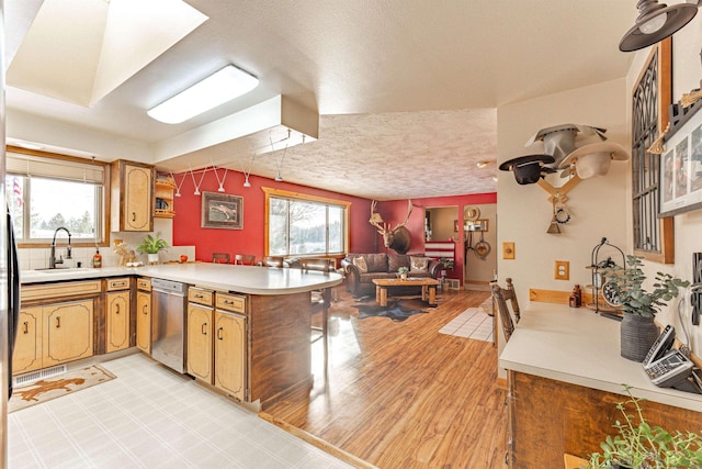 kitchen featuring a healthy amount of sunlight, sink, kitchen peninsula, and dishwasher