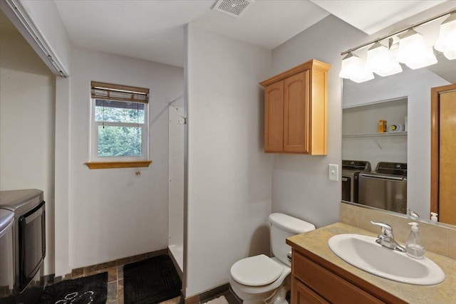 bathroom with vanity, toilet, washer and clothes dryer, and walk in shower