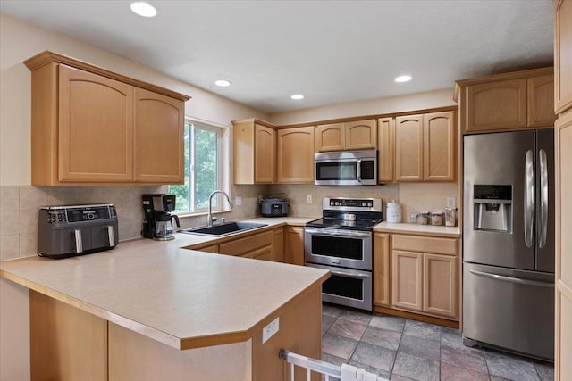 kitchen with light brown cabinetry, sink, appliances with stainless steel finishes, kitchen peninsula, and decorative backsplash