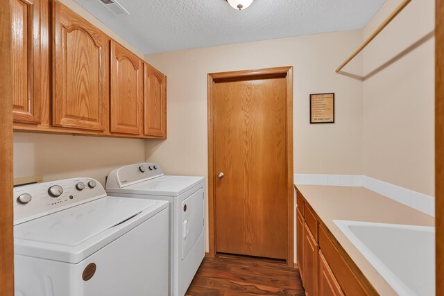 laundry area with sink, cabinets, a textured ceiling, dark hardwood / wood-style floors, and washing machine and dryer