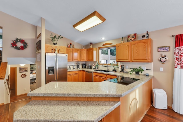 kitchen featuring sink, appliances with stainless steel finishes, dark hardwood / wood-style floors, light stone countertops, and kitchen peninsula