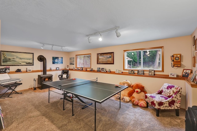 playroom with plenty of natural light, carpet flooring, and a wood stove