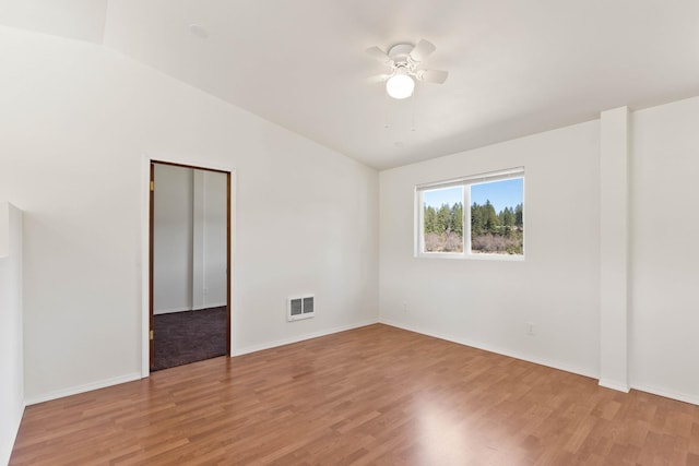 empty room with lofted ceiling, hardwood / wood-style flooring, and ceiling fan