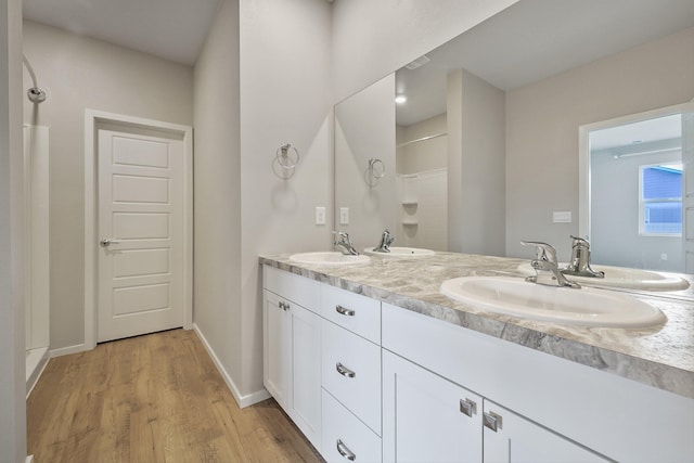 bathroom with hardwood / wood-style floors, vanity, and walk in shower