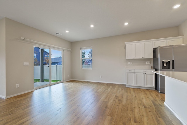 kitchen featuring white cabinets, stainless steel fridge, and light hardwood / wood-style flooring