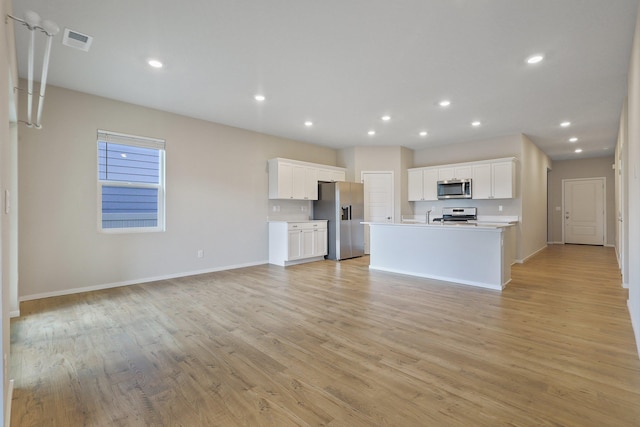 kitchen featuring light hardwood / wood-style flooring, appliances with stainless steel finishes, white cabinetry, and a kitchen island with sink