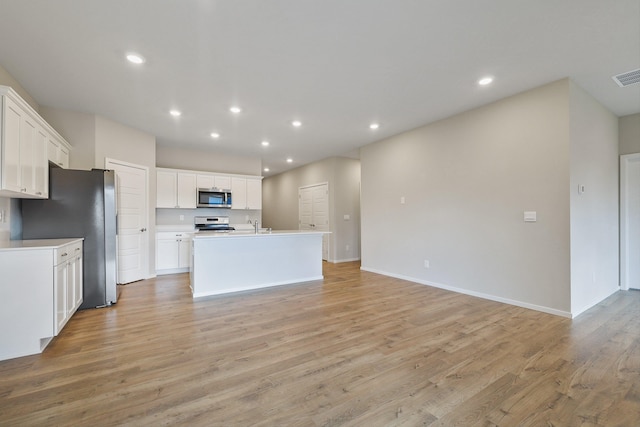 kitchen featuring appliances with stainless steel finishes, light hardwood / wood-style floors, white cabinetry, and a kitchen island with sink