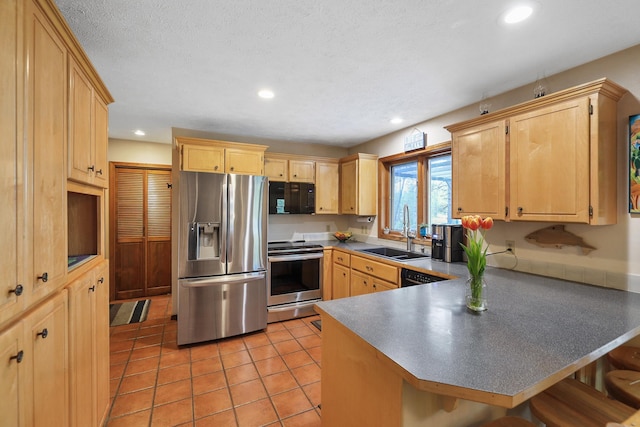 kitchen featuring light brown cabinetry, a breakfast bar, sink, kitchen peninsula, and black appliances