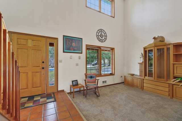 entryway featuring a towering ceiling, plenty of natural light, and carpet