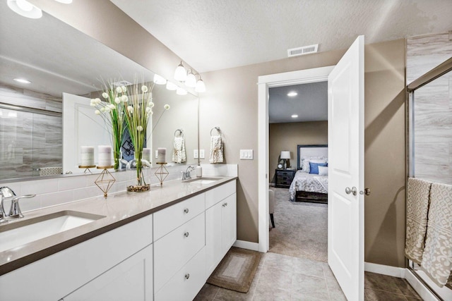 bathroom featuring a shower with door, vanity, tile patterned flooring, and a textured ceiling