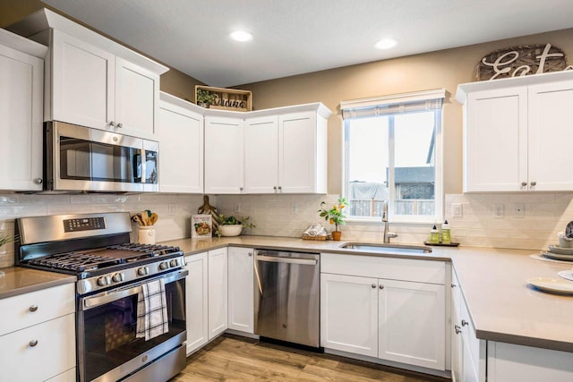 kitchen with stainless steel appliances, white cabinetry, sink, and backsplash