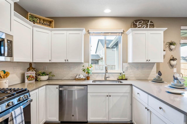 kitchen with white cabinetry, sink, backsplash, and stainless steel appliances