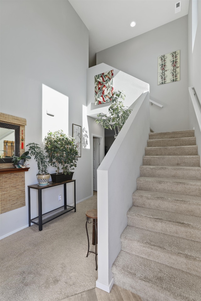 stairs with a high ceiling and carpet floors