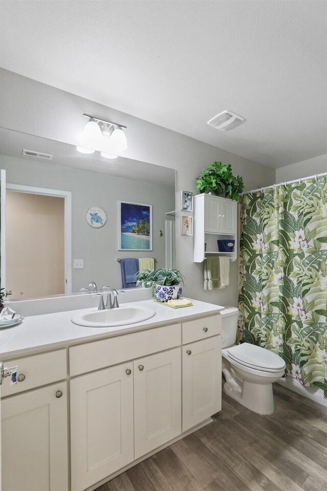 bathroom with vanity, hardwood / wood-style flooring, curtained shower, and toilet