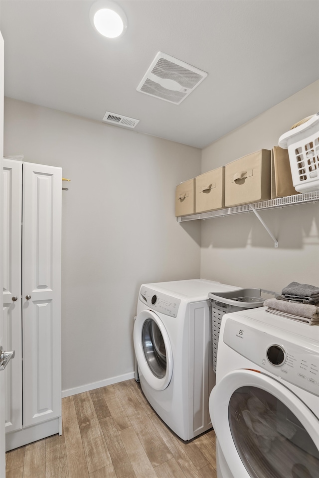 laundry area with washer and dryer and light hardwood / wood-style floors