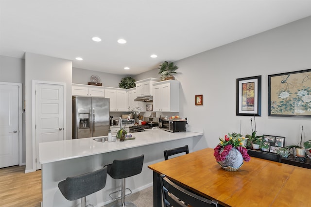 kitchen featuring stainless steel appliances, white cabinetry, a breakfast bar area, and kitchen peninsula