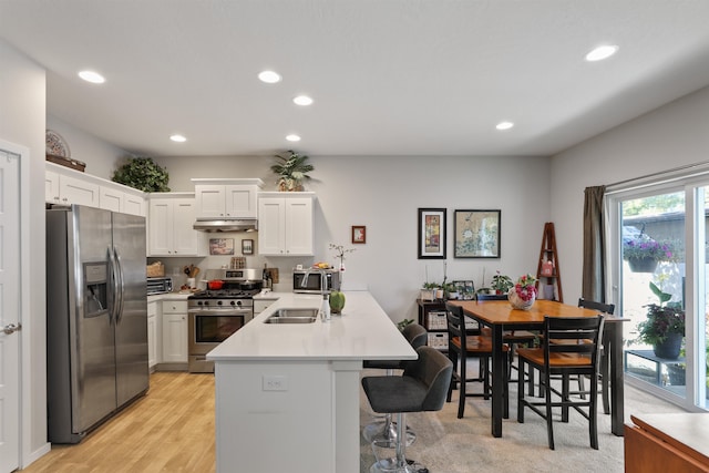 kitchen featuring sink, light hardwood / wood-style flooring, appliances with stainless steel finishes, a kitchen breakfast bar, and white cabinets