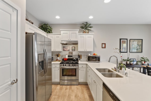 kitchen with white cabinetry, appliances with stainless steel finishes, sink, and light hardwood / wood-style flooring