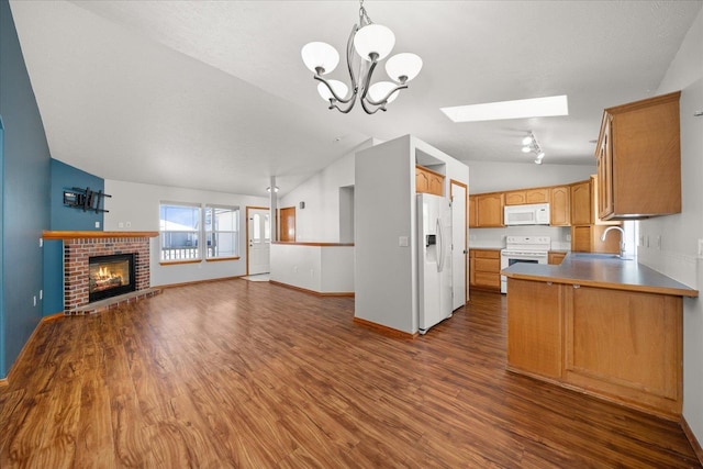 kitchen featuring sink, white appliances, hanging light fixtures, lofted ceiling with skylight, and kitchen peninsula