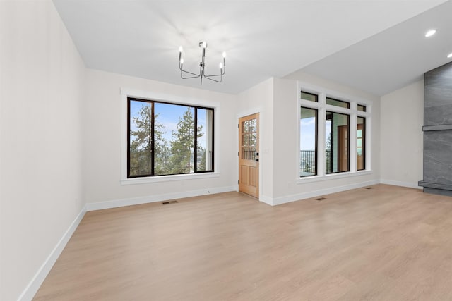 unfurnished living room with a notable chandelier and light hardwood / wood-style flooring