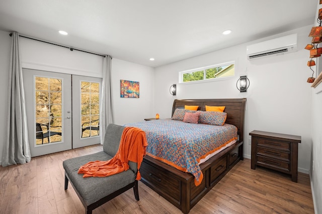 bedroom with a wall mounted air conditioner, access to outside, french doors, and wood-type flooring