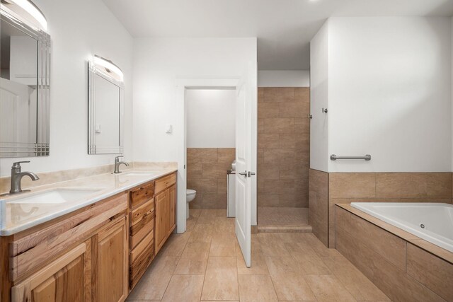 bathroom featuring vanity, tiled bath, tile walls, and toilet